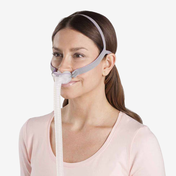 Woman wearing ResMed AirFit P10 CPAP For Her nasal pillows mask with QuietAir vent technology.